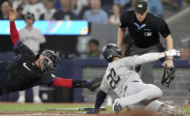 New York Yankees outfielder Juan Soto (22) slides safe into home as Toronto Blue Jays catcher Danny Jansen (9) fails to make the tag during fourth inning American League MLB baseball action in Toronto, Friday, June 28, 2024. THE CANADIAN PRESS/Chris Young/The Canadian Press via AP)