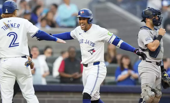 Toronto Blue Jays' George Springer, center, celebrates his three-run home run against the New York Yankees with Justin Turner (2) during the first inning of a baseball game in Toronto on Thursday, June 27, 2024. (Frank Gunn/The Canadian Press via AP)