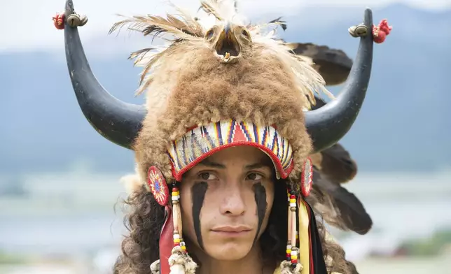 Ota Bluehorse, a member of the Spirit Lake Tribe, wears a headdress adorned with bison horns during a naming ceremony for a white buffalo calf at the Buffalo Field Campaign headquarters in West Yellowstone, Mont., Wednesday, June 26, 2024. The reported birth of a white buffalo calf in Yellowstone National Park fulfills a Lakota prophecy that portends better times. (AP Photo/Sam Wilson)