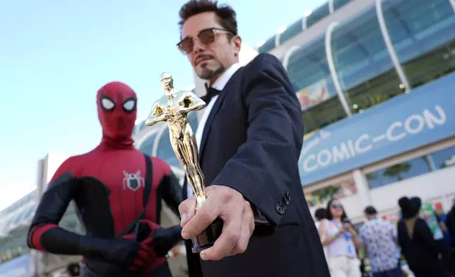 Alex Decleves, right, dressed as Tony Stark from the film "Iron Man," and Kevin Delgado, left, dressed as Spider-man, pose together before preview night for Comic-Con International, Wednesday, July 24, 2024, in San Diego. Decleves is holding a replica Oscar in reference to "Iron Man" actor Robert Downey Jr.'s Best Supporting Actor win for "Oppenheimer" at this year's Academy Awards. (AP Photo/Chris Pizzello)