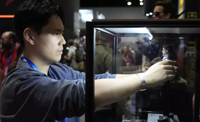 Viper Zheng of collectibles brand INART adjusts a Michael Jackson figure for display during preview night for Comic-Con International, Wednesday, July 24, 2024, in San Diego. (AP Photo/Chris Pizzello)