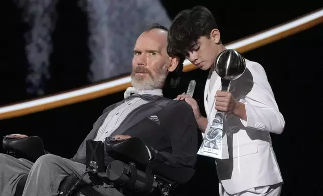 Steve Gleason, left, with his son Rivers, right, accept the Arthur Ashe Award for Courage at the ESPY awards on Thursday, July 11, 2024, at the Dolby Theatre in Los Angeles. (AP Photo/Mark J. Terrill)