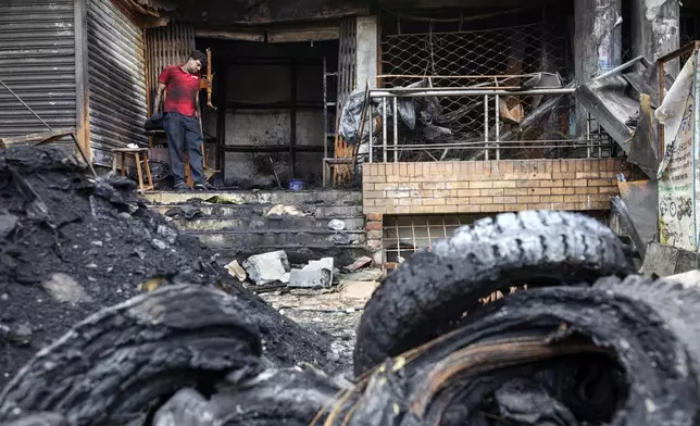 Nizam Uddin looks at the burnt tyres in front of his shop which was set on fire during a clash two days ago which turned into vandalism along the Dhaka Chittagong highway in Dhaka, Bangladesh, Tuesday, July 23, 2024. Internet and mobile data services are still down despite apparent calm in Bangladesh following a verdict that scaled back a controversial quota system for government jobs after weeks of relentless protests that turned deadly. (AP Photo/Rajib Dhar)