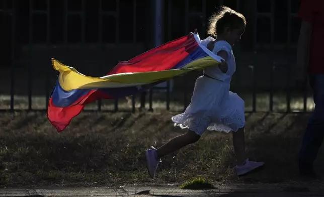 A youth runs with a Venezuelan flag outside a polling station set up at the Venezuelan embassy in Brasilia, Brazil, on the day of the Venezuelan presidential election, Sunday, July 28, 2024. (AP Photo/Eraldo Peres)