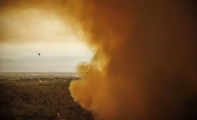 A helicopter drops water as the Thompson Fire burns, Tuesday, July 2, 2024, in Oroville, Calif. (AP Photo/Ethan Swope)