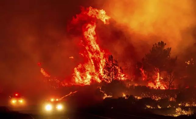 Flames leap above fire vehicles as the Park Fire jumps Highway 36 near Paynes Creek in Tehama County, Calif., Friday, July 26, 2024. (AP Photo/Noah Berger)