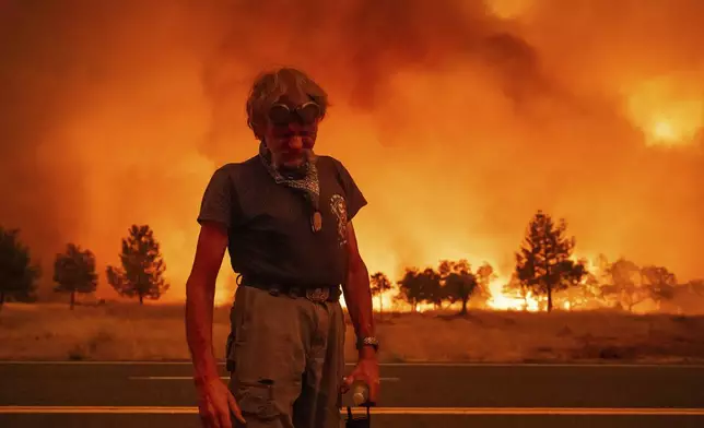 Grant Douglas pauses while evacuating as the Park Fire jumps Highway 36 near Paynes Creek in Tehama County, Calif., on Friday, July 26, 2024. (AP Photo/Noah Berger)