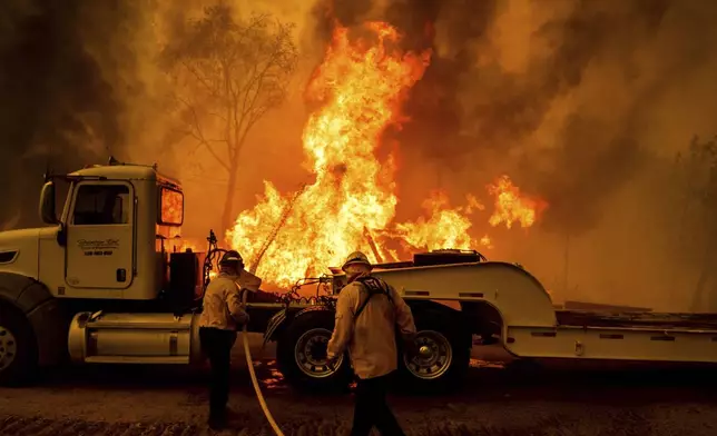 Firefighters spray water as the Park Fire tears though the Cohasset community in Butte County, Calif., on Thursday, July 25, 2024. (AP Photo/Noah Berger)