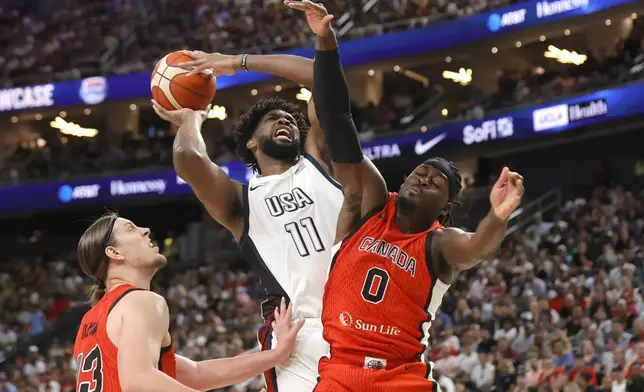 United States center Joel Embiid (11) drives to the basket against Canada center Kelly Olynyk (13) and point guard Luguentz Dort (0) during the first half of an exhibition basketball game Wednesday, July 10, 2024, in Las Vegas. (AP Photo/Steve Marcus)