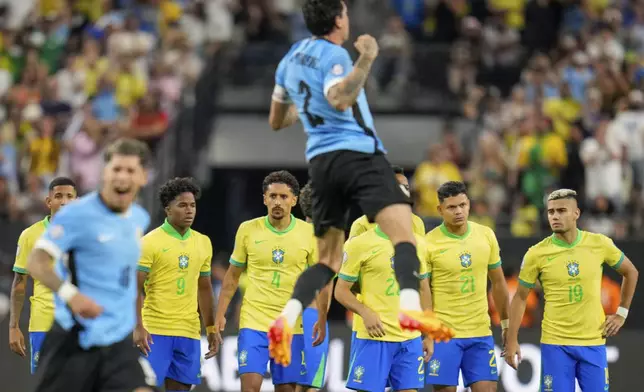 Payers of Brazil stand on the midfield as players of Uruguay celebrate their win in a penalty shootout during a Copa America quarterfinal soccer match in Las Vegas, Saturday, July 6, 2024. (AP Photo/Julio Cortez)