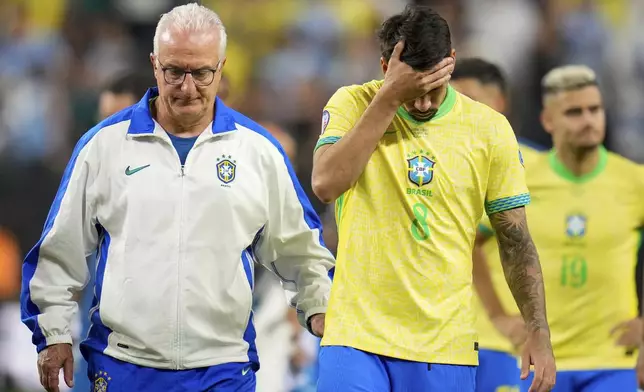 Brazil's coach Dorival Junior, right escorts off the field Lucas Paqueta (8) and teammates after their lost in a penalty shootout against Uruguay during a Copa America quarterfinal soccer match in Las Vegas, Saturday, July 6, 2024. (AP Photo/Julio Cortez)