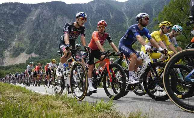 Slovenia's Tadej Pogacar, wearing the overall leader's yellow jersey, Poland's Michal Kwiatkowski, second left, and France's Clement Russo, third from right, rides in the pack during the fifth stage of the Tour de France cycling race over 177.4 kilometers (110.2 miles) with start in Saint-Jean-de-Maurienne and finish in Saint-Vulbas, France, Wednesday, July 3, 2024. (AP Photo/Jerome Delay)