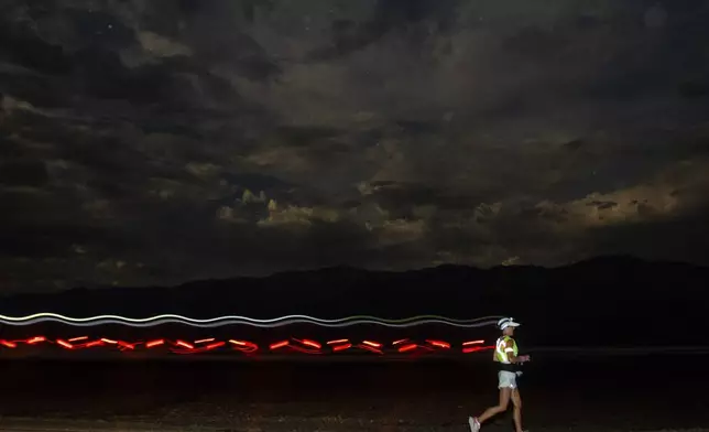 A runner races with a headlamp and a safety vest under a moon light sky during the Badwater 135 mile (217 kilometer) ultramarathon in Death Valley, Calif., Monday, July 22, 2024. (AP Photo/Ty ONeil)