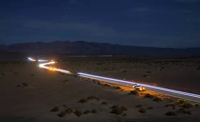 This long exposure image shows the path of runners and their support vehicles under a moon light sky on California Route 190 during the Badwater 135 mile (217 kilometer) ultramarathon in Death Valley, Calif., Tuesday, July 23, 2024. (AP Photo/Ty ONeil)