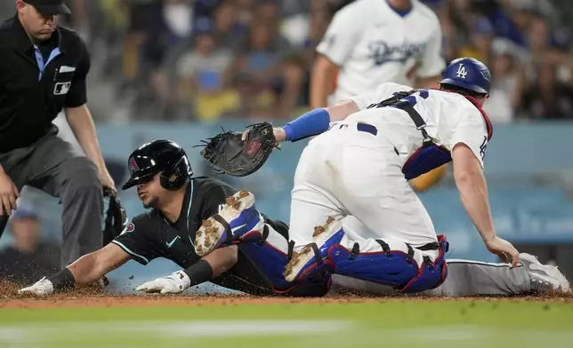 Arizona Diamondbacks' Gabriel Moreno, left, slides home past Los Angeles Dodgers catcher Will Smith to score off a bunt single by Jake McCarthy during the eighth inning of a baseball game against the Los Angeles Dodgers, Tuesday, July 2, 2024, in Los Angeles. (AP Photo/Ryan Sun)