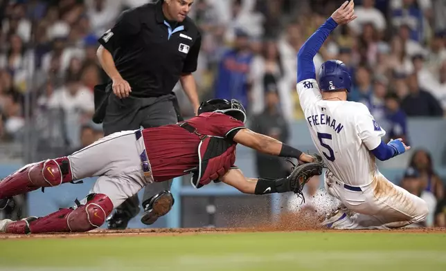 Los Angeles Dodgers' Freddie Freeman, right, is tagged out by Arizona Diamondbacks catcher Gabriel Moreno as he tried to score from third on the line out by Miguel Rojas during the third inning of a baseball game Wednesday, July 3, 2024, in Los Angeles. (AP Photo/Mark J. Terrill)