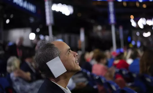 Arizona delegate Joe Neglia place a paper on his ear during the Republican National Convention Tuesday, July 16, 2024, in Milwaukee. (AP Photo/Jae C. Hong)