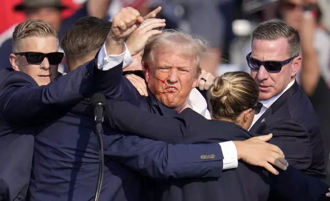 Republican presidential candidate former President Donald Trump pumps his fist as he is helped off the stage at a campaign event in Butler, Pa., on Saturday, July 13, 2024. (AP Photo/Gene J. Puskar)