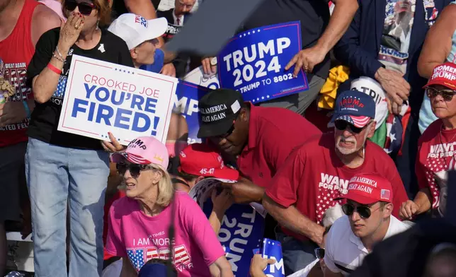 Members of the crowd react as U.S. Secret Service agents surround Republican presidential candidate former President Donald Trump at a campaign event in Butler, Pa., on Saturday, July 13, 2024. (AP Photo/Gene J. Puskar)