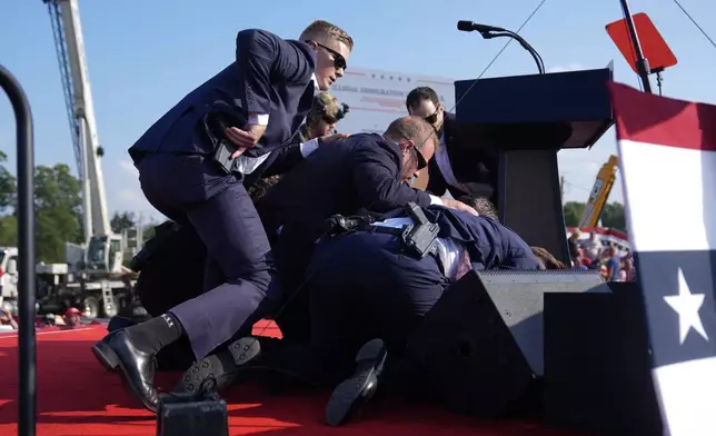 Republican presidential candidate former President Donald Trump is covered by U.S. Secret Service agents at a campaign rally, Saturday, July 13, 2024, in Butler, Pa. (AP Photo/Evan Vucci)