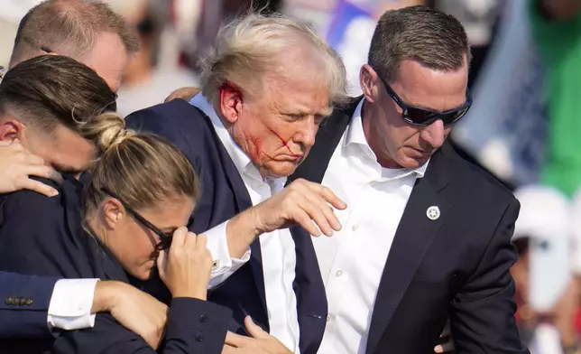 Republican presidential candidate former President Donald Trump is helped off the stage at a campaign event in Butler, Pa., on Saturday, July 13, 2024. (AP Photo/Gene J. Puskar)