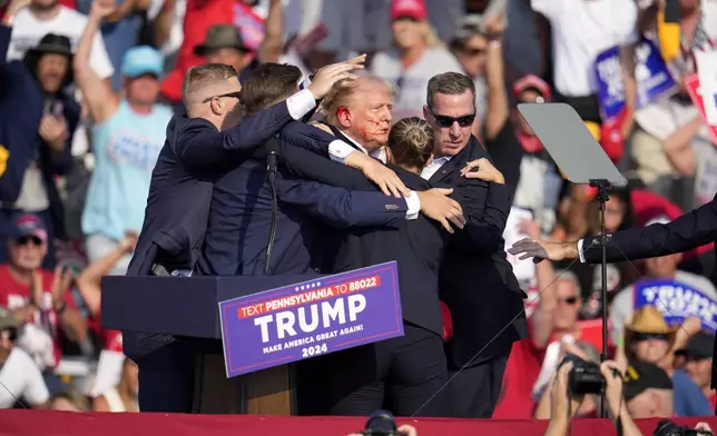 Republican presidential candidate former President Donald Trump is helped off the stage at a campaign event in Butler, Pa., Saturday, July 13, 2024. (AP Photo/Gene J. Puskar)