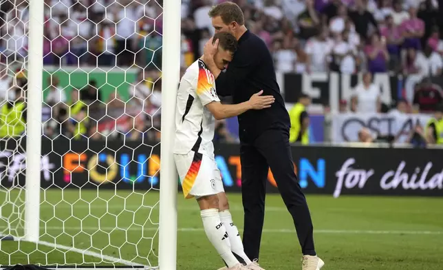 Germany's Joshua Kimmich is hugged by Germany's head coach Julian Nagelsmann at the end of a quarter final match between Germany and Spain at the Euro 2024 soccer tournament in Stuttgart, Germany, Friday, July 5, 2024. (AP Photo/Matthias Schrader)