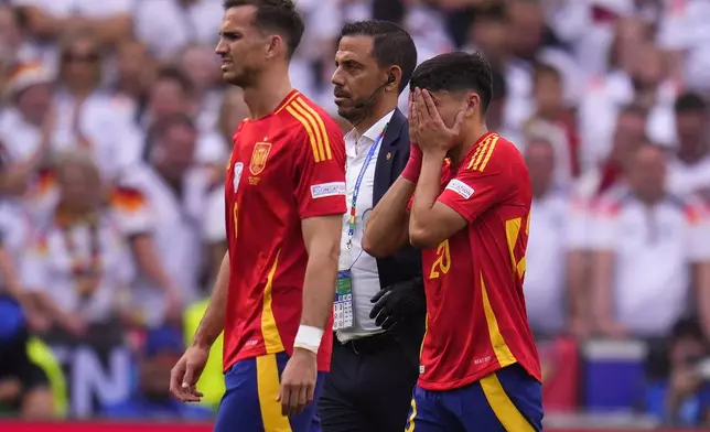 Spain's Pedri, right, covers his face after suffering an injury during a quarter final match between Germany and Spain at the Euro 2024 soccer tournament in Stuttgart, Germany, Friday, July 5, 2024. (AP Photo/Manu Fernandez)