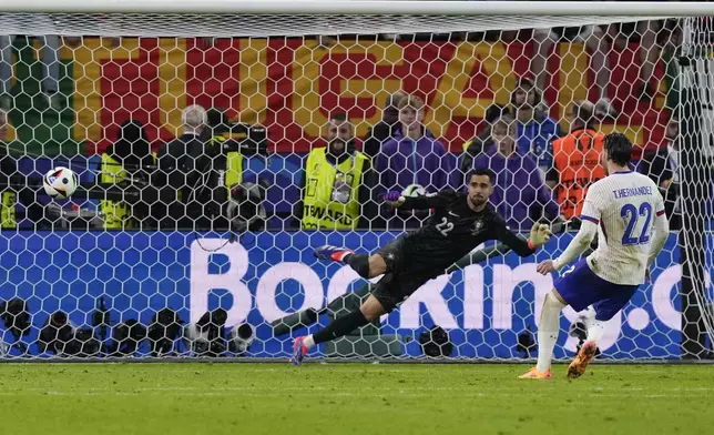 Theo Hernandez of France, right, scores the deciding goal in a shootout to win a quarter final match between Portugal and France at the Euro 2024 soccer tournament in Hamburg, Germany, Friday, July 5, 2024. (AP Photo/Frank Augstein)