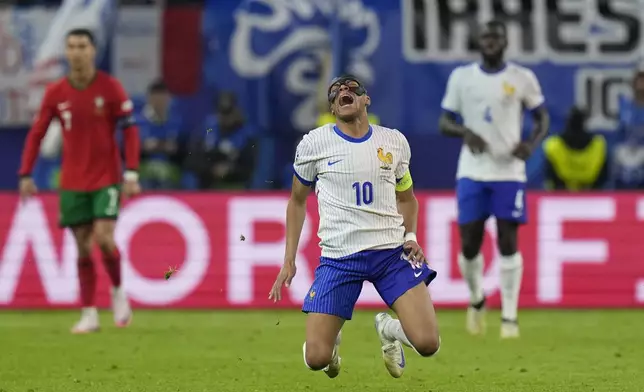 Kylian Mbappe of France, center, falls after a collision with Portugal's Joao Palhinha during a quarter final match at the Euro 2024 soccer tournament in Hamburg, Germany, Friday, July 5, 2024. (AP Photo/Hassan Ammar)