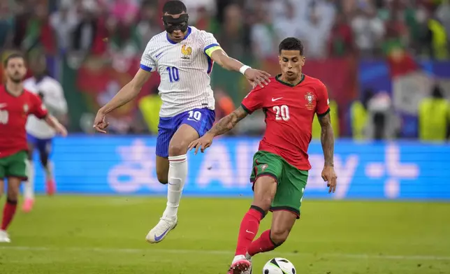 Kylian Mbappe of France challenges for the ball with Portugal's Joao Cancelo during a quarter final match between Portugal and France at the Euro 2024 soccer tournament in Hamburg, Germany, Friday, July 5, 2024. (AP Photo/Andreea Alexandru)