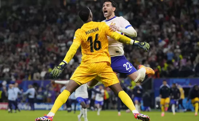 Theo Hernandez of France, right, celebrates with goalkeeper Mike Maignan after scores the winning goal to defeat Portugal during a quarter final match at the Euro 2024 soccer tournament in Hamburg, Germany, Friday, July 5, 2024. (AP Photo/Hassan Ammar)