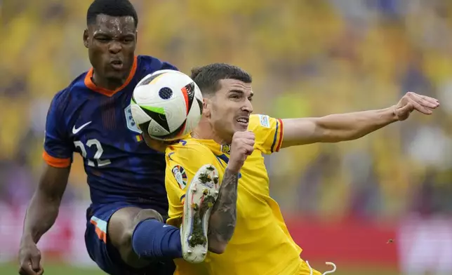Denzel Dumfries of the Netherlands fights for the ball against Romania's Valentin Mihaila during a round of sixteen match between Romania and the Netherlands at the Euro 2024 soccer tournament in Munich, Germany, Tuesday, July 2, 2024. (AP Photo/Antonio Calanni)