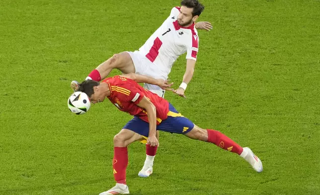Spain's Robin Le Normand competes for the ball with Georgia's Khvicha Kvaratskhelia during a round of sixteen match at the Euro 2024 soccer tournament in Cologne, Germany, Sunday, June 30, 2024. (AP Photo/Andreea Alexandru)