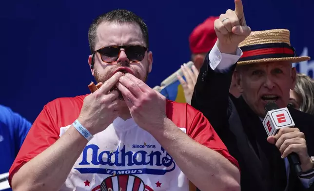 Patrick Bertoletti stuffs hot dogs into his mouth during the men's division in Nathan's Famous Fourth of July hot dog eating contest, Thursday, July 4, 2024, at Coney Island in the Brooklyn borough of New York. Bertoletti ate 58 hot dogs. (AP Photo/Julia Nikhinson)