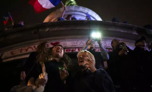 People gather at the Republique plaza after the second round of the legislative election, Sunday, July 7, 2024, in Paris. Surprise polling projections in France say a leftist coalition that came together to try to keep the far right from power has won the most parliamentary seats in runoff elections after a high turnout among voters. (AP Photo/Louise Delmotte)