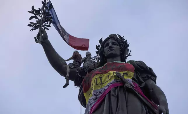 Statue of Republique plaza is decorated by flags as people gather at a protest against the far-right, Wednesday, July 3, 2024 in Paris. French opposition parties and associations are trying to block a landslide victory for Marine Le Pen's far-right National Rally in next Sunday's second round of legislative elections. (AP Photo/Louise Delmotte)