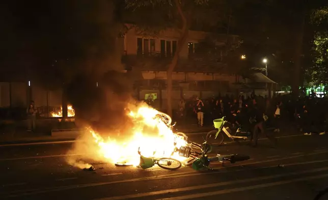 Bicycles burn during tensions near Republique plaza following the second round of the legislative elections, Sunday, July 7, 2024 in Paris. A coalition of the French left that quickly banded together to beat a surging far right in legislative elections won the most seats in parliament but not a majority, according to polling projections Sunday, a stunning outcome that threatens to plunge the country into political and economic turmoil. (AP Photo/Aurelien Morissard)