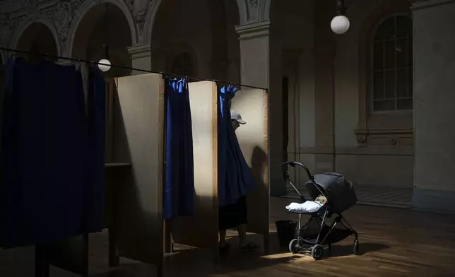 A voter leaves a booth at a polling station after voting in the second round of the legislative elections, in Lyon, central France, Sunday, July 7, 2024. France votes Sunday in pivotal runoff elections that could hand a historic victory to Marine Le Pen's far-right National Rally and its inward-looking, anti-immigrant vision — or produce a hung parliament and years of political deadlock. (AP Photo/Laurent Cipriani)