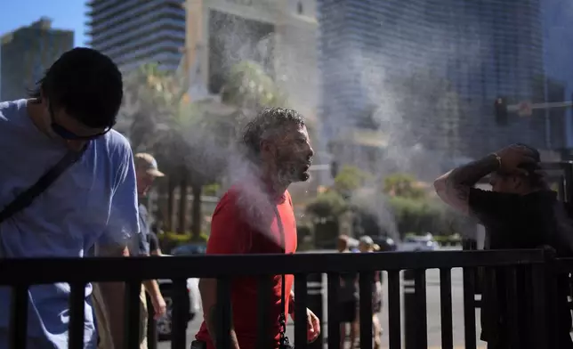 People cool off in misters along the Las Vegas Strip, Sunday, July 7, 2024, in Las Vegas. A heat wave is spreading across the Western U.S., the National Weather Service said, sending many residents in search of a cool haven from the dangerously high temperatures. (AP Photo/John Locher)