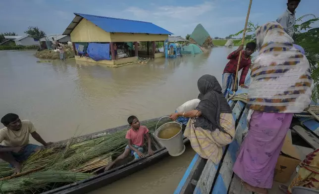 People shift from a boat to another to reach a shelter due to flooding in Morigaon district in the northeastern Indian state of Assam, India, Wednesday, July 3, 2024. (AP Photo/Anupam Nath)