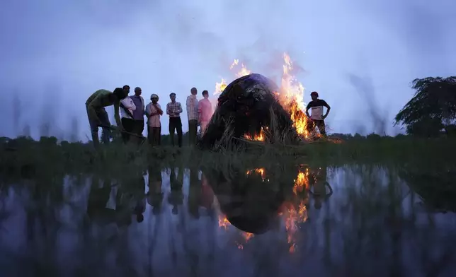 Flames rise from the cremation pyre of Savitri Devi, 50, who died during a stampede, in Ramnagar, in the northern Indian state of Uttar Pradesh, Wednesday, July 3, 2024. Devi was among more than 120 people who died in a stampede last week at a religious festival in northern India, as the faithful surged toward the preacher and chaos ensued among the attendees. (AP Photo/Rajesh Kumar Singh)