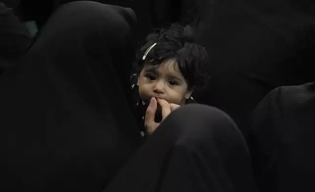 An Iranian Shiite Muslim woman feeds her child as they attend Ashoura mourning ritual, commemorating the 7th century martyrdom of Prophet Muhammad's grandson, Hussein, in the battle of Karbala in present-day Iraq, at the old main bazaar of Tehran, Iran, Tuesday, July 16, 2024. Shiites represent over 10% of the world's 1.8 billion Muslims and view Hussein as the rightful successor to the Prophet Muhammad. (AP Photo/Vahid Salemi)