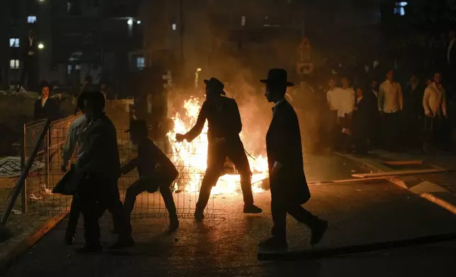 Ultra-Orthodox Jewish men burn trash during a protest against army recruitment in Jerusalem on Sunday, June 30, 2024. Israel's Supreme Court last week ordered the government to begin drafting ultra-Orthodox men into the army, a landmark ruling seeking to end a system that has allowed them to avoid enlistment into compulsory military service. (AP Photo/Ohad Zwigenberg)
