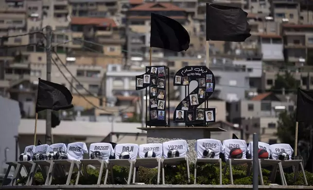 Photos of the12 children and teens, killed in a rocket strike at a soccer field, and chairs with their names are seen displayed on a roundabout in the village of Majdal Shams, in the Israeli-annexed Golan Heights, Tuesday, July 30, 2024. (AP Photo/Leo Correa)