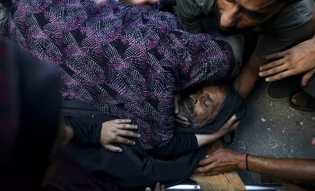 Relatives mourn over the body of a Palestinian man killed in an Israeli airstrike on a U.N.-run school-turned-shelter that killed at least 16 people in the Nusseirat refugee camp in the Gaza Strip, Saturday, July 6, 2024, according to Gaza’s Health Ministry. Israel’s military said it struck several “terrorists” operating in the area of the school and had tried to lessen the risk to civilians. (AP Photo/Saher Alghorra)