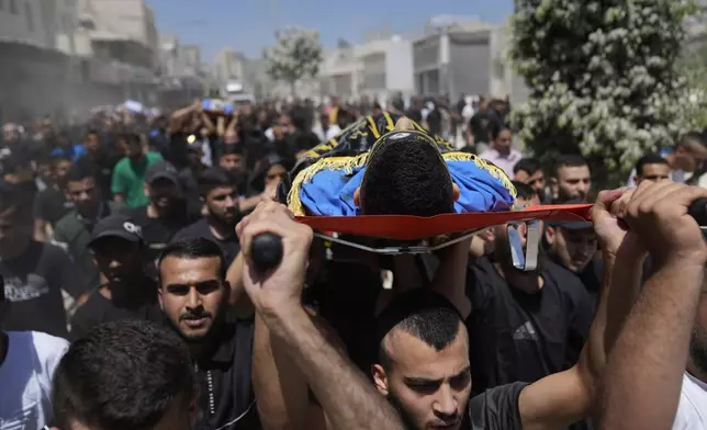Mourners carry the bodies of four Palestinians, killed by an Israeli airstrike late Tuesday, during their funeral in the West Bank refugee camp of Nur Shams, near Tulkarem, Wednesday, July 3, 2024. Palestinian health officials say four Palestinians were killed by an Israeli airstrike in a refugee camp in the northern West Bank late Tuesday. Israel's military said an aircraft struck a group of militants who were planting explosives in Nur Shams refugee camp near Tulkarem. (AP Photo/Nasser Nasser)