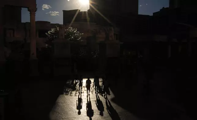 People walk in the sun along the Las Vegas Strip, Sunday, July 7, 2024, in Las Vegas. The city set an all time record high of 120 F (48.8 C) Sunday as a heat wave spread across the Western U.S. sending many residents in search of a cool haven from the dangerously high temperatures. (AP Photo/John Locher)