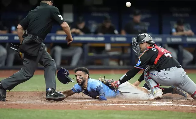 Tampa Bay Rays' Jose Caballero, center, steals home plate as the ball skips away from Miami Marlins catcher Nick Fortes, right, during the seventh inning of a baseball game Tuesday, July 30, 2024, in St. Petersburg, Fla. Making the call is home plate umpire Tripp Gibson. (AP Photo/Christopher O'Meara)