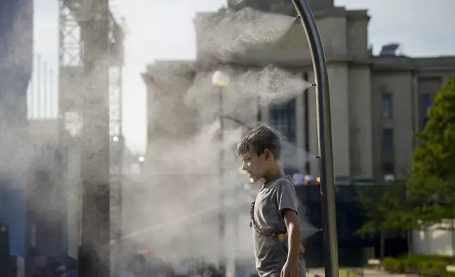 Eli, 10, cools off under a misting fountain on a hot afternoon during the 2024 Summer Olympics, Monday, July 29, 2024, in Paris, France. (AP Photo/Vadim Ghirda)